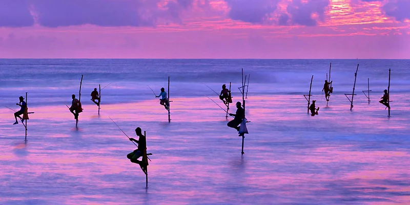 Pescadores sobre zancos en el mar al atardecer, en la costa sur de Sri Lanka