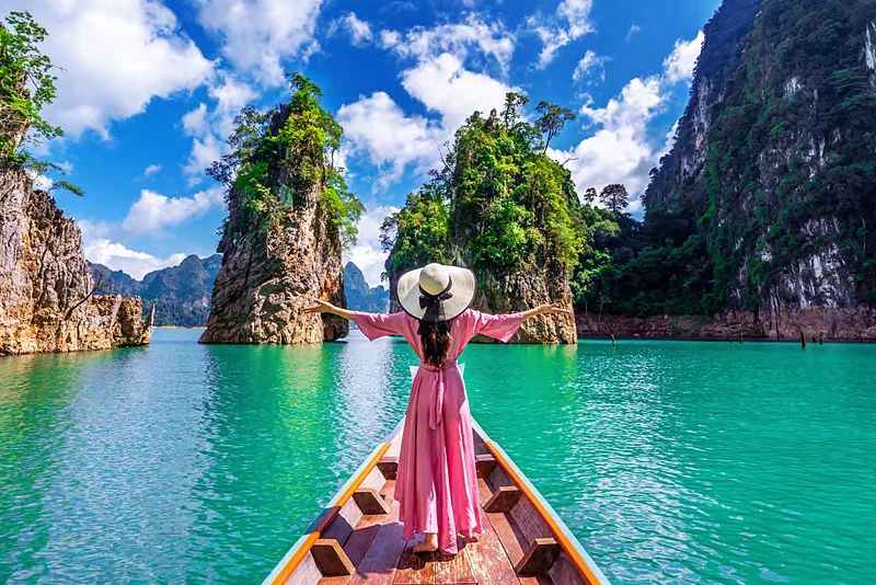 Viajera en la proa de un bote entre islotes del lago de Khao Sok