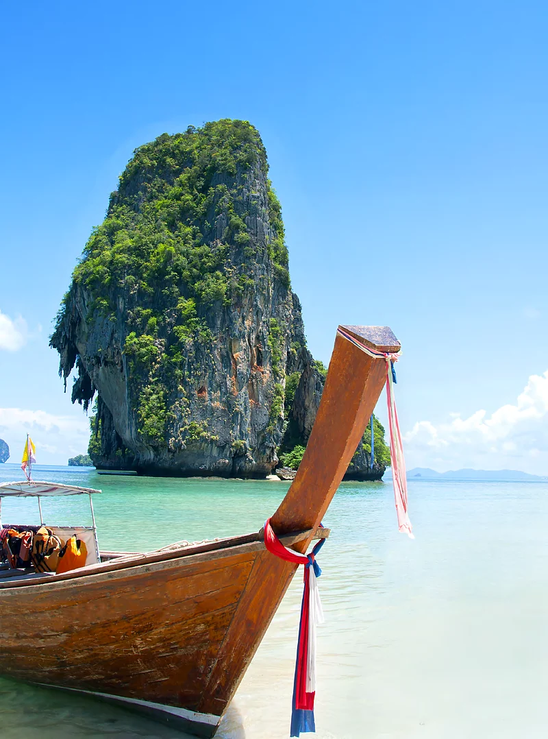 Bote de cola larga frente a un peñón de piedra caliza en Krabi