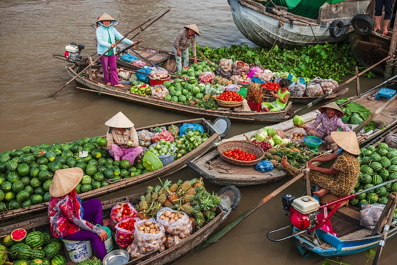 Vendedoras con sombrero cónico en botes cargados de frutas en un mercado flotante