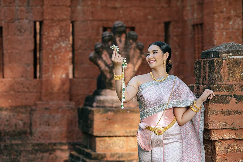 Mujer con traje tradicional tailandés entre las ruinas de un templo antiguo